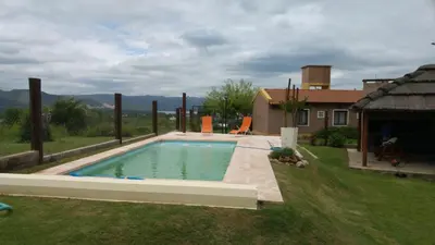 a swimming pool in a yard next to a house at Cabañas Villa del Mirador in Bialet Massé