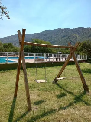 a wooden swing set in a field with a pool at La Simona in Cortaderas