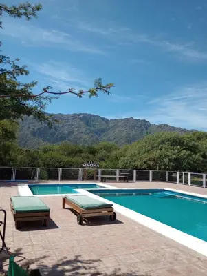 a swimming pool with two benches and mountains in the background at La Simona in Cortaderas
