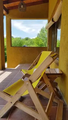 a yellow lounge chair on the porch of a house at Posada Casa de Piedra in Los Reartes
