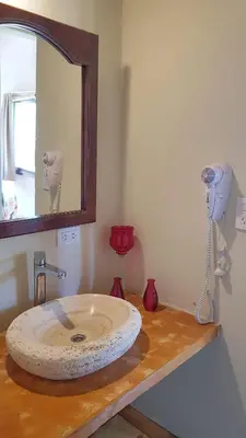 a bathroom with a sink with a hair dryer on a counter at Posada Casa de Piedra in Los Reartes