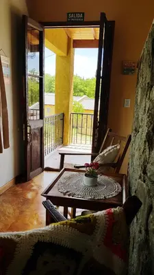 a living room with a table and a door to a balcony at Posada Casa de Piedra in Los Reartes