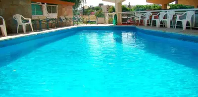 a swimming pool with blue water and white chairs at Hotel Playa in Villa Carlos Paz