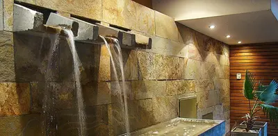 a stone wall with two water fountains in a bathroom at Hotel Playa in Villa Carlos Paz
