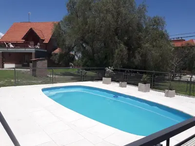 a blue swimming pool in a yard with a house at Chalet Nuevo Amanecer in Merlo