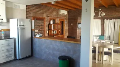a kitchen with a refrigerator and a table with chairs at Chalet Nuevo Amanecer in Merlo