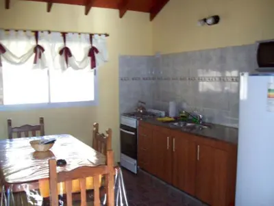 a kitchen with a table and a refrigerator at Cabañas Toay Merlo San Luis in Merlo