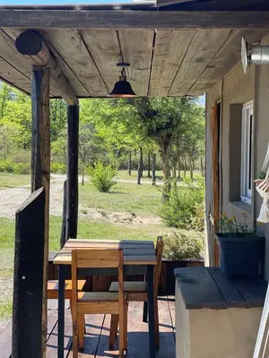 a wooden table and chairs on a porch with a view of a park at Las Quimeras in Nono
