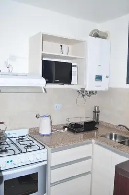 a kitchen with white cabinets and a stove top oven at Dpto Edificio Tempo in Villa Carlos Paz