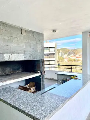 a kitchen with a stone fireplace in a building at Dpto Edificio Tempo in Villa Carlos Paz