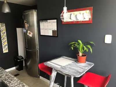 a table and red chairs in a kitchen with a refrigerator at Departamento Premiun En Zona Centro in Cordoba