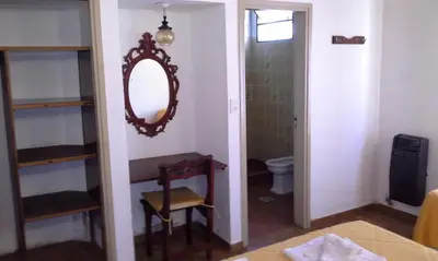 a bathroom with a mirror and a table and a toilet at Amanitas Hotel in Villa Carlos Paz