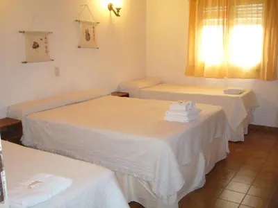 a room with three beds with white sheets and towels at Amanitas Hotel in Villa Carlos Paz