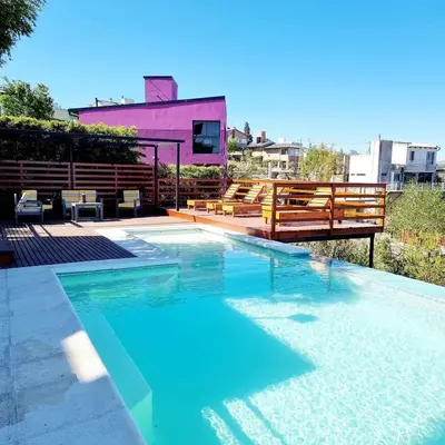 a swimming pool with benches and a house at Altos del Lago in Villa Carlos Paz