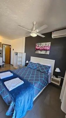 a bedroom with a blue bed and a ceiling fan at Altos del Lago in Villa Carlos Paz