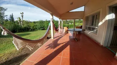 a porch with a hammock on a house at casa de campo en Villa Los Aromos Cordoba in Villa Los Aromos