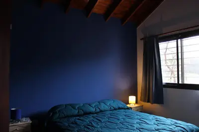 a blue bedroom with a bed and a window at Casa Crisolito in Merlo