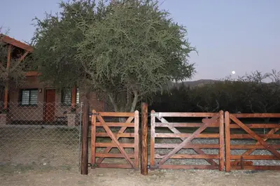 a wooden gate in front of a house with a tree at Casa Crisolito in Merlo
