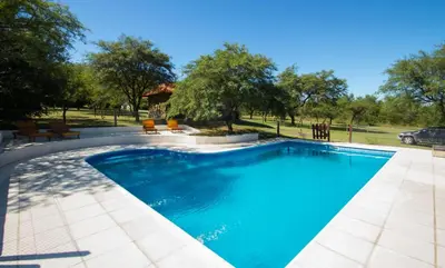 a swimming pool with blue water in a yard at El Refugio Casas de Campo in Villa General Belgrano