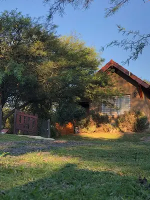 a house with a tree and a bench in front of it at El Refugio Casas de Campo in Villa General Belgrano