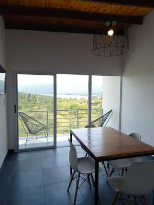 a dining room with a table and chairs and a balcony at Complejo Joansa in Villa Santa Cruz del Lago