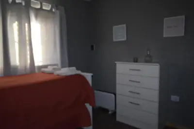 a bedroom with a bed and a dresser and a window at Complejo Joansa in Villa Santa Cruz del Lago