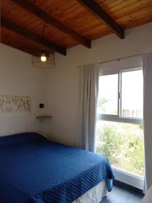 a bedroom with a blue bed and a large window at Complejo Joansa in Villa Santa Cruz del Lago