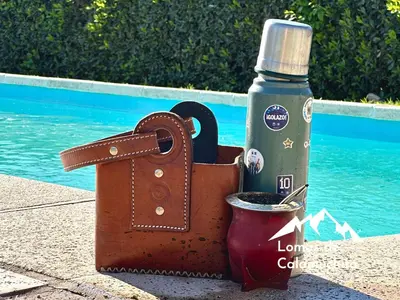 a bottle of water and a leather bag with a drink at Cabañas Lomas de Calamuchita in Santa Rosa de Calamuchita