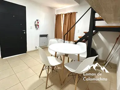 a dining room with a white table and white chairs at Cabañas Lomas de Calamuchita in Santa Rosa de Calamuchita