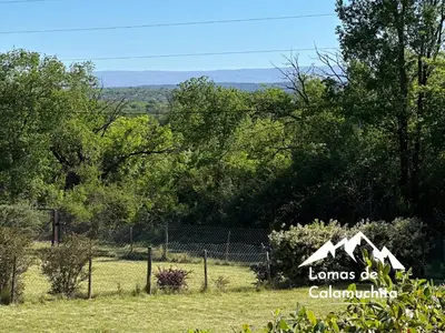 a house in a field with a fence and trees at Cabañas Lomas de Calamuchita in Santa Rosa de Calamuchita