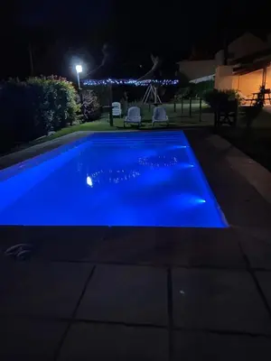 a blue swimming pool at night with two chairs at Cabañas Lomas de Calamuchita in Santa Rosa de Calamuchita