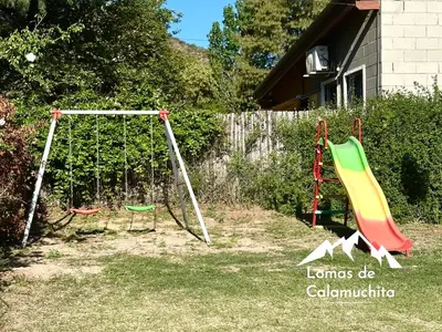 a playground with two swings in a yard at Cabañas Lomas de Calamuchita in Santa Rosa de Calamuchita