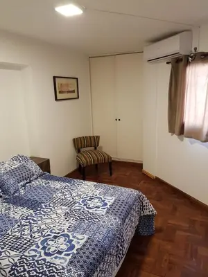 a bedroom with a bed and a chair at Apartamento Carlucci in Cordoba