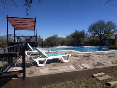 a swimming pool with two lounge chairs and a table at El Naranjero Apart in Carpintería