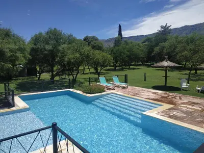 a large swimming pool with two chairs and an umbrella at El Naranjero Apart in Carpintería