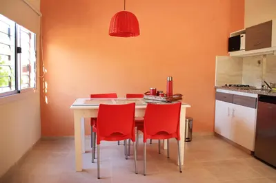 a kitchen with a table and red chairs at El Naranjero Apart in Carpintería