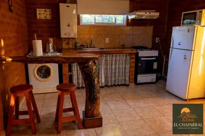 a kitchen with a table and a stove and a refrigerator at Cabaña El Chaparral Villa Dolores, Traslasierra 1 in Piedra Pintada