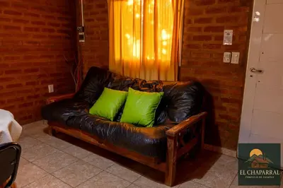 a leather couch with two green pillows on it at Cabaña El Chaparral Villa Dolores, Traslasierra 1 in Piedra Pintada