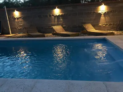 a swimming pool with chairs and lights next to a wall at El Viejo Vagon in Mina Clavero
