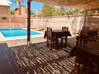 a patio with a table and chairs next to a pool at El Viejo Vagon in Mina Clavero