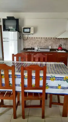 a kitchen with a table and chairs and a kitchen with a refrigerator at El Viejo Vagon in Mina Clavero