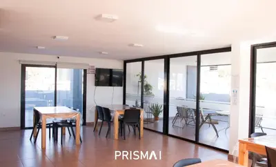 a dining room with tables and chairs and windows at Edificio PRISMA I in Villa Carlos Paz