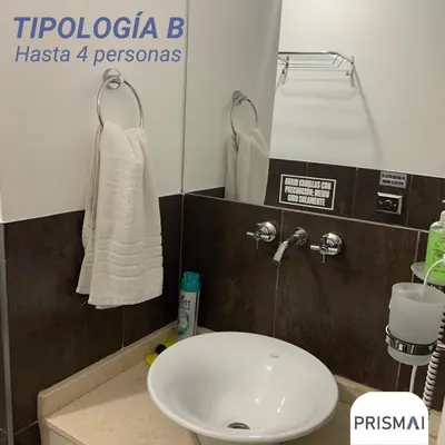 a bathroom with a sink and a toilet and towels at Edificio PRISMA I in Villa Carlos Paz