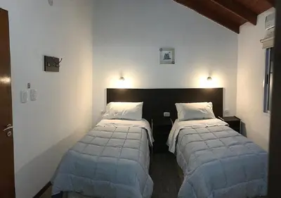 two beds in a room with white walls at Hostería Boutique El Puente Adults Only in Merlo