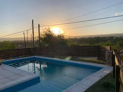 a swimming pool with the sunset in the background at CABAÑA EN TANTI in Tanti