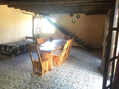 a dining room with a wooden table and a staircase at CABAÑA EN TANTI in Tanti