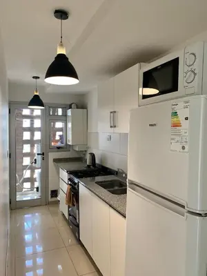 a white kitchen with a refrigerator and a sink at ALOHA Güemes Premium, 2 dorm con Vista a las Sierras in Cordoba