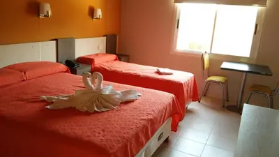 a hotel room with two beds with red sheets at Aparts Piscu Yaco Almendros in Merlo