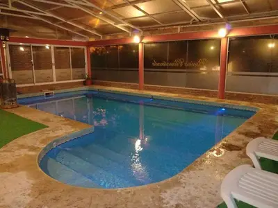 a large swimming pool with blue water in a building at Aparts Piscu Yaco Almendros in Merlo