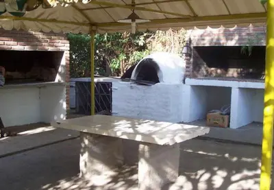 a picnic table under a tent with a pizza oven at Aparts Piscu Yaco Almendros in Merlo